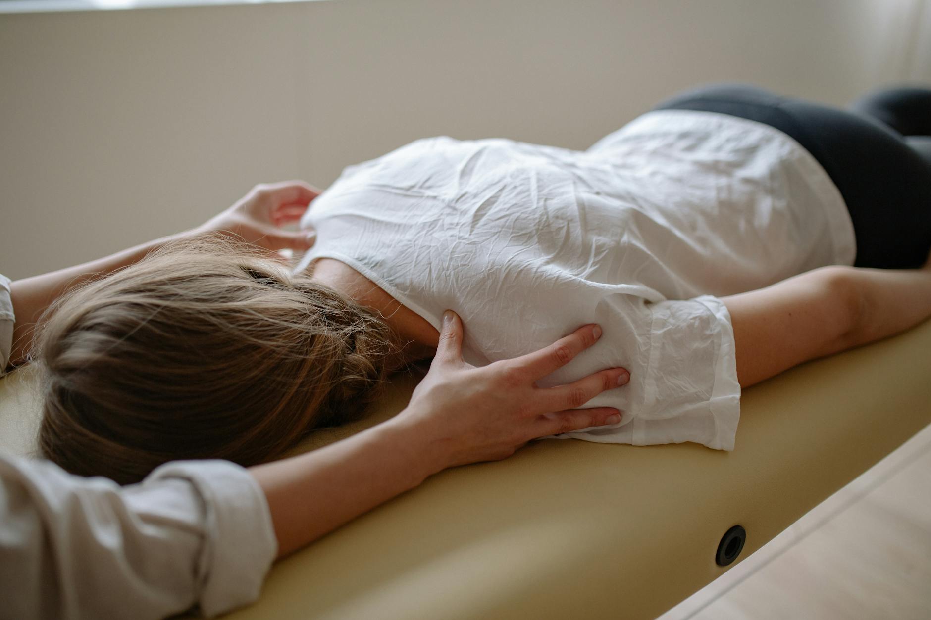 hands of massage therapist and lying girl